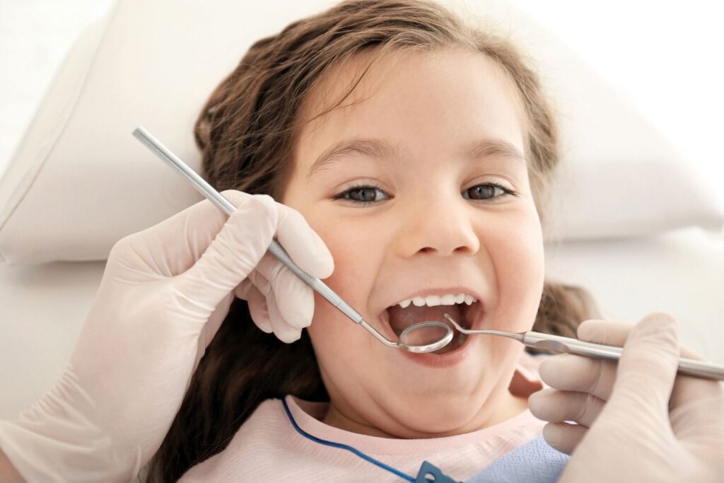 İlk diş hekimi muayenesinde bir çocuğun ağız ve diş gelişiminin değerlendirilmesini gösteren klinik ortam görseli.