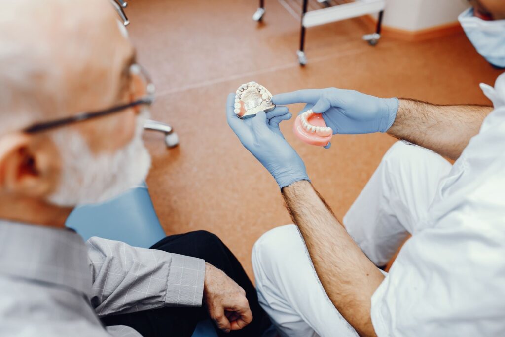 Overdenture implant üzerine oturan hareketli protezin ağız içindeki konumunu gösteren diş hekimliği görseli.