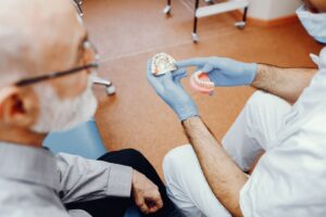 Overdenture implant üzerine oturan hareketli protezin ağız içindeki konumunu gösteren diş hekimliği görseli.